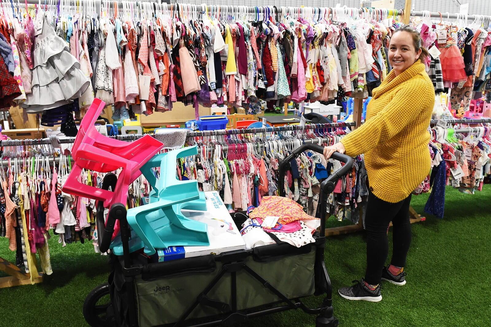 Two friends shop together—one mom wears her baby girl—as they find great deals at their local JBF sale.
